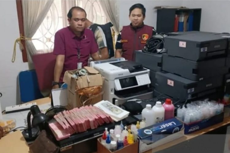 Petugas di tempat produksi uang palsu yang digrebek di Bogor bersama barang bukti. (Foto: ANT).