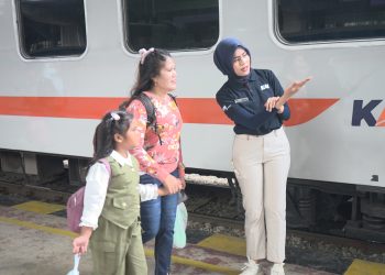 Petugas stasiun KA Medan saat memberikan arahan kepada penumpang.